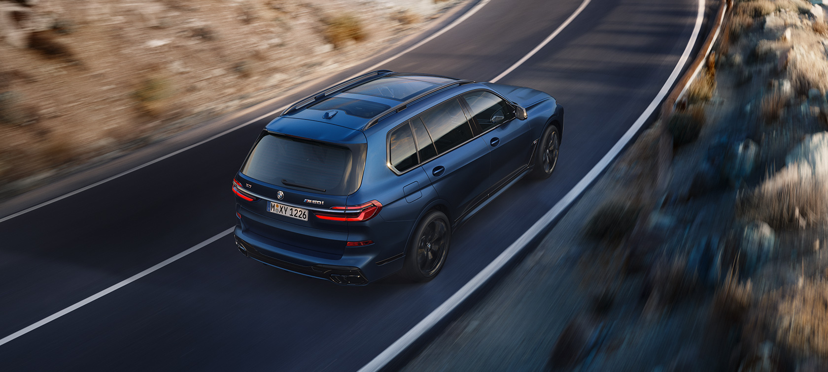 BMW X7 M60i xDrive G07 LCI Frozen Marina Bay Blue, kolmen neljäsosan näkymä liikkeellä olevan auton takaa lintuperspektiivistä BMW X7 M60i xDrive G07 LCI Frozen Marina Bay Blue, kolmen neljäsosan näkymä tiellä liikkeellä olevan auton takaa lintuperspektiivistä