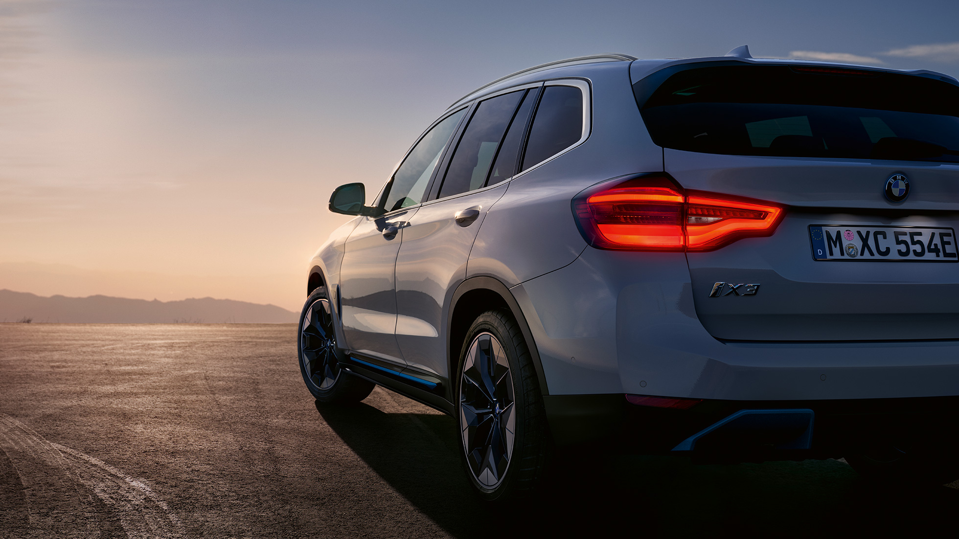BMW iX3 G08, kolmen neljäsosan näkymä tiellä olevan auton perästä BMW iX3 G08 2020 metalliväri Mineral White, kolmen neljäsosan näkymä tiellä olevan auton perästä