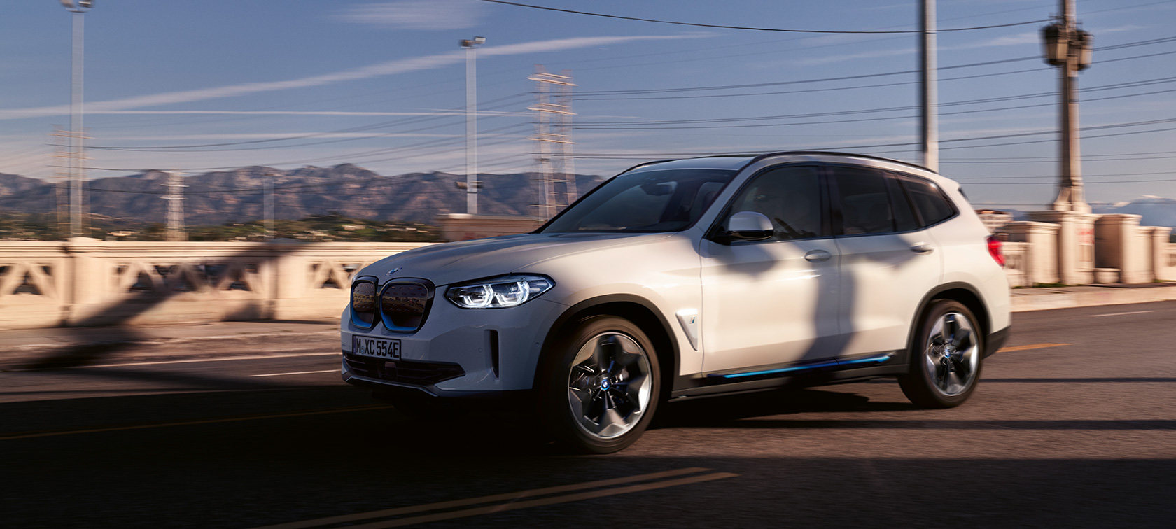 BMW iX3 G08 metalliväri Mineral White, kolmen neljäsosan näkymä tiellä ajavan auton keulasta BMW iX3 G08 2020 metalliväri Mineral White, kolmen neljäsosan näkymä tiellä ajavan auton keulasta