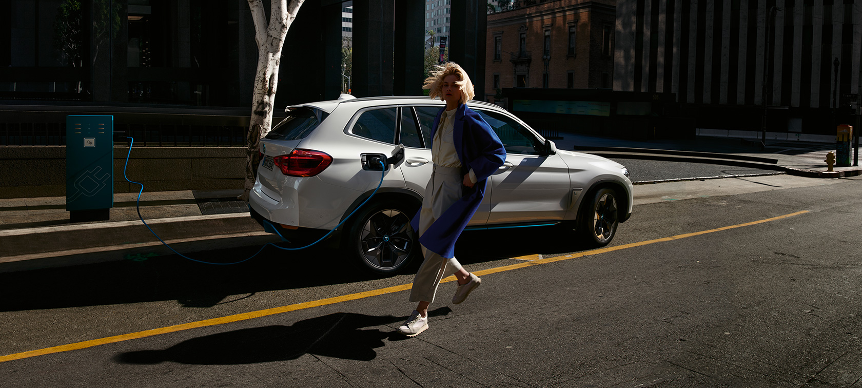 BMW iX3 G08, sivunäkymä julkisen latauspisteen luona BMW iX3 G08 2020 metalliväri Mineral White, sivunäkymä julkisen latauspisteen luona