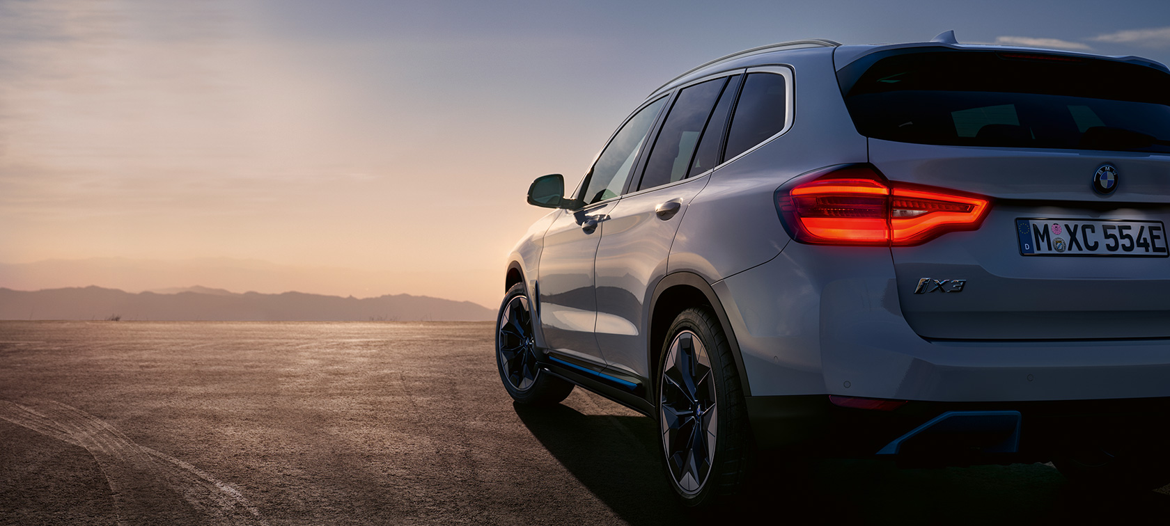BMW iX3 G08 pysähtyneenä kadulla BMW iX3 G08 2020 metalliväri Mineral White, kolmen neljäsosan näkymä kadulle pysähtyneen auton perästä