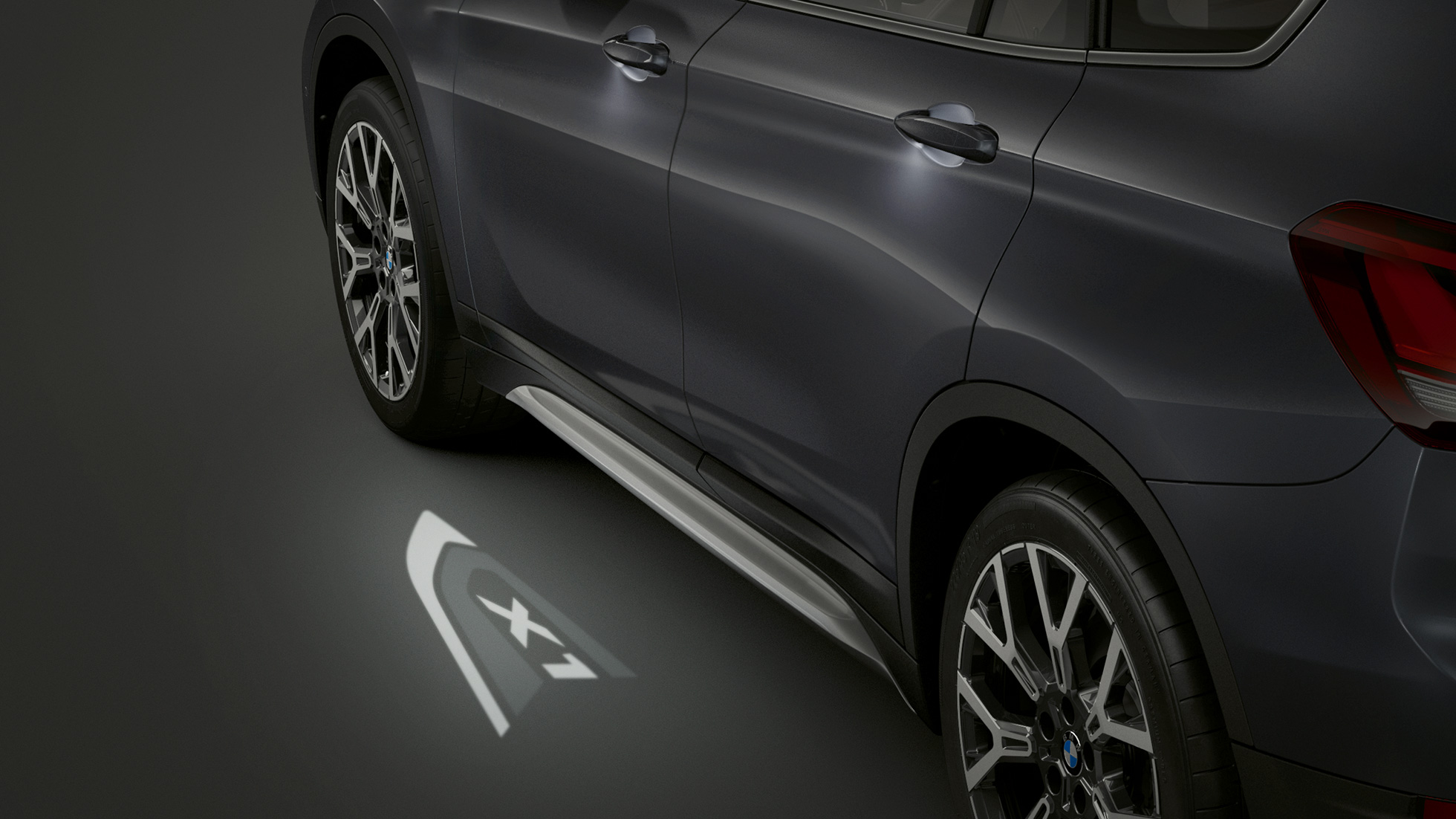 BMW X1, LED-valoilla heijastettu ”X1”. BMW X1, sivunäkymä, kuva LED-valoilla heijastetusta mallitunnuksesta ”X1”.