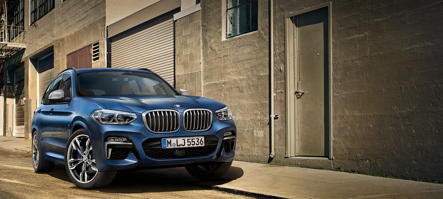 BMW X3 M40i, kuva pysähdyksissä olevasta autosta talon seinän edessä BMW X3 M40i, kuva pysähdyksissä olevasta autosta talon seinän edessä