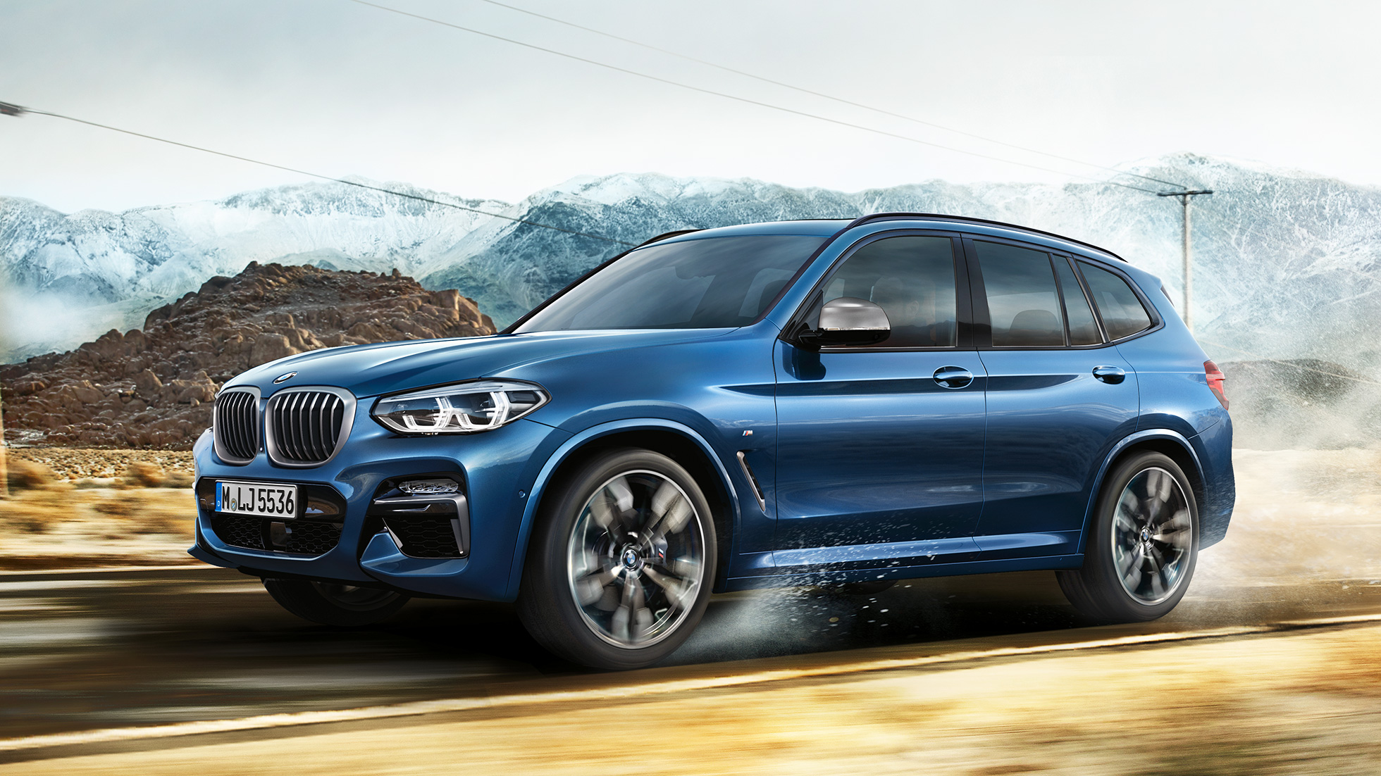 BMW X3 M40i, kokokuva vanteesta ja lokasuojasta vuoriston edessä BMW X3 M40i, kokokuva vanteesta ja lokasuojasta vuoriston edessä