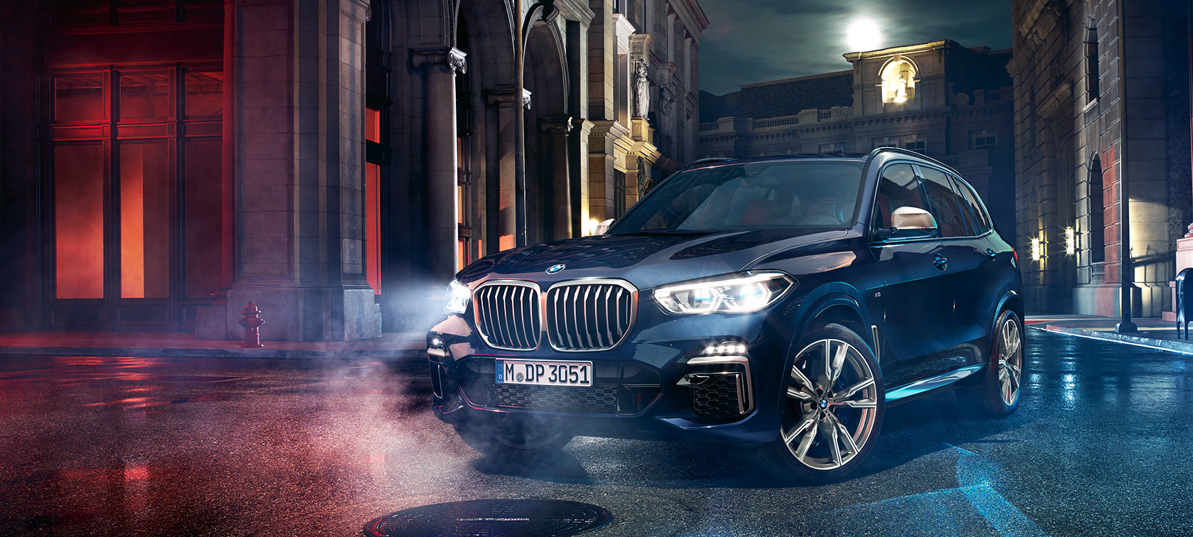 BMW X5 M50d kadulla BMW X5 M50d paikallaan öisessä suurkaupunkimaisemassa