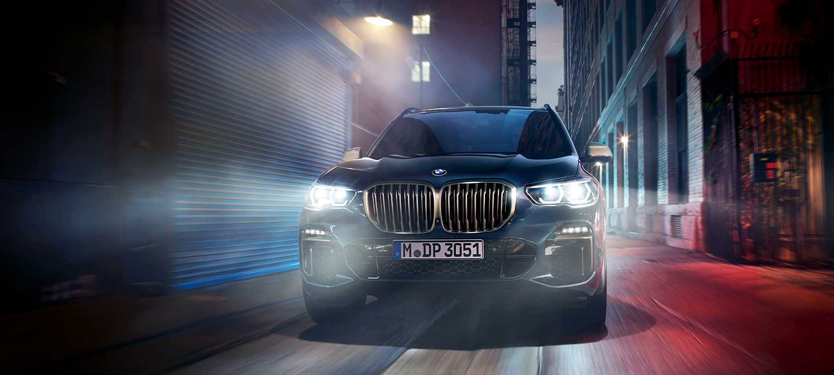 BMW X5 M50d liikkeellä BMW X5 M50d ajaa öisen kaupungin kadulla