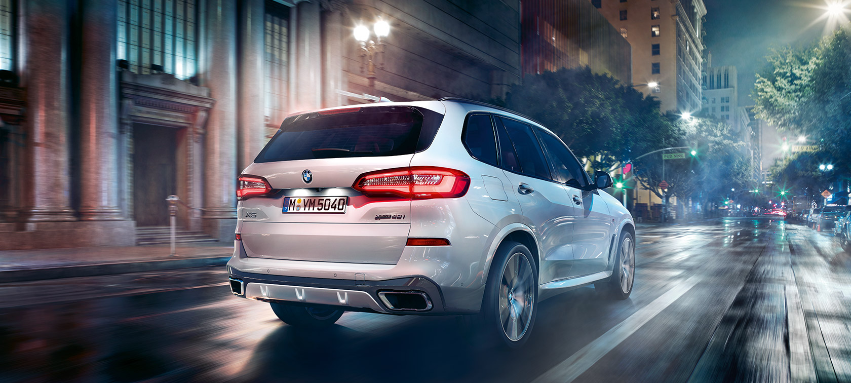 BMW X5, kolmen neljäsosan näkymä liikkeellä olevan auton takaosasta BMW X5 G05 2018 metalliväri Mineral White, kolmen neljäsosan näkymä liikkeellä olevan auton takaosasta