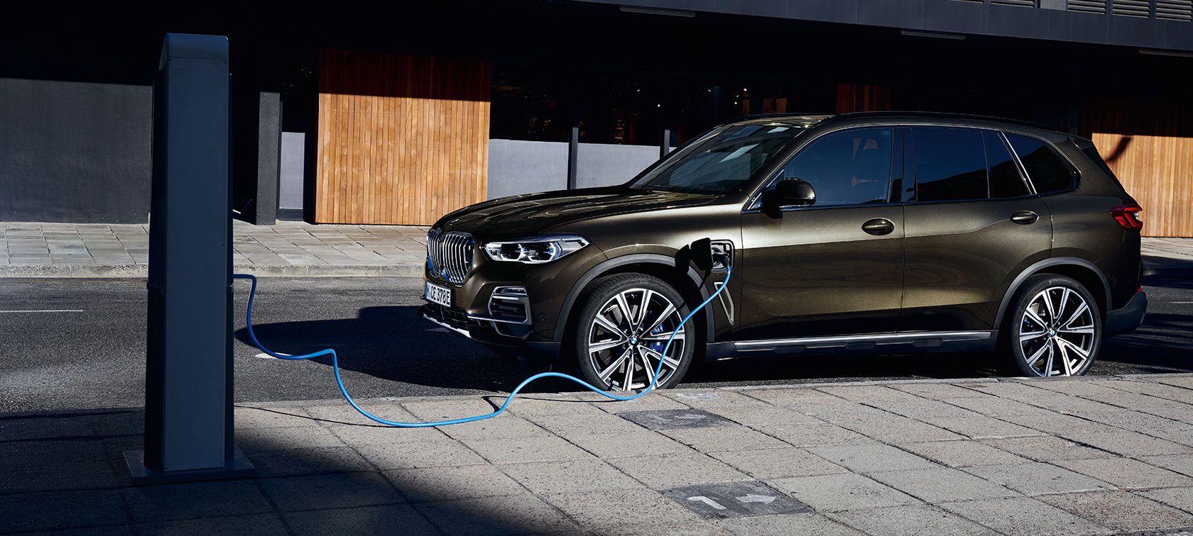 Plug-in hybrid BMW X5 xDrive45e G05, kolmen neljäsosan näkymä sivulta Plug-in hybrid BMW X5 xDrive45e G05, kolmen neljäsosan näkymä sivulta latauksessa