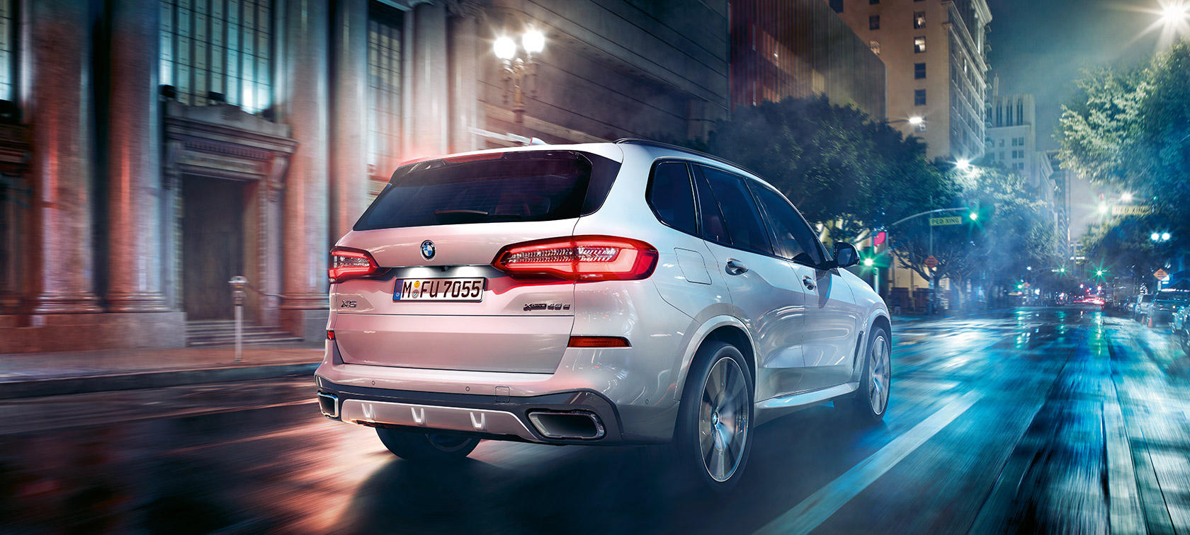 BMW X5, kolmen neljäsosan näkymä liikkeellä olevan auton perästä BMW X5 G05 2021 metalliväri Mineral White, kolmen neljäsosan näkymä liikkeellä olevan auton perästä