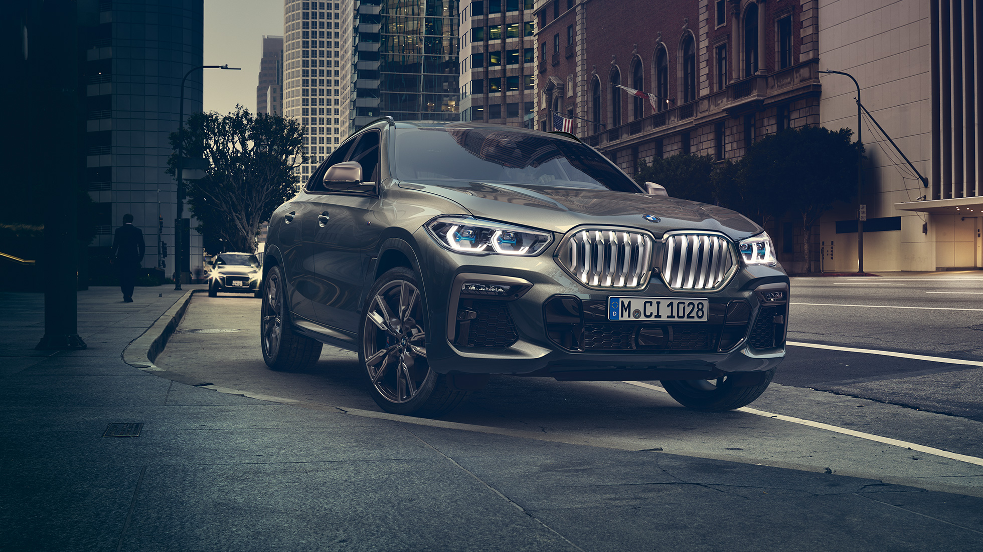 BMW X6, adaptiivinen M-alusta Professional. BMW X6, 3/4-näkymä edestä kaupunkinäkymän edustalla.