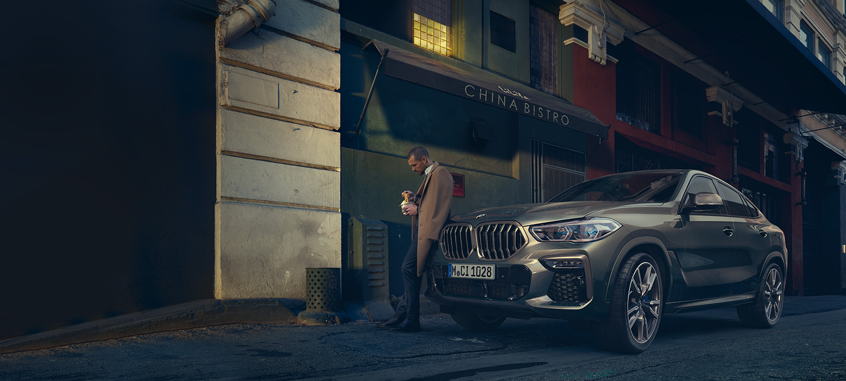 BMW X6, kolmen neljäsosan näkymä liikkeellä olevasta autosta takaa katsottuna BMW X6 G06 2021 metalliväri Manhatten, kolmen neljäsosan näkymä liikkeellä olevasta autosta takaa katsottuna