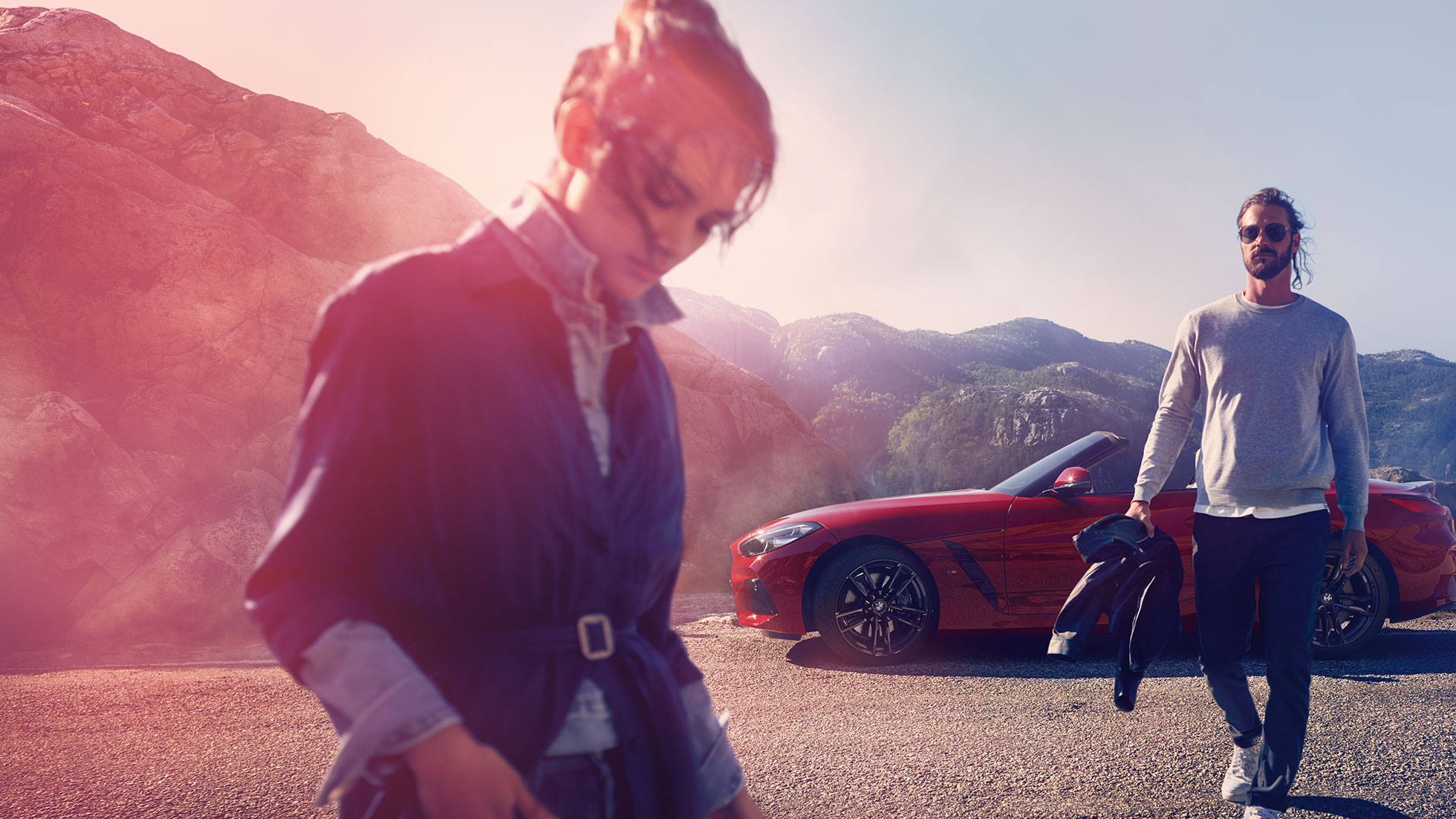 BMW Z4 Roadster vuoristomaisemassa Nainen ja mies BMW Z4 Roadsterin edessä vuoristomaisemassa