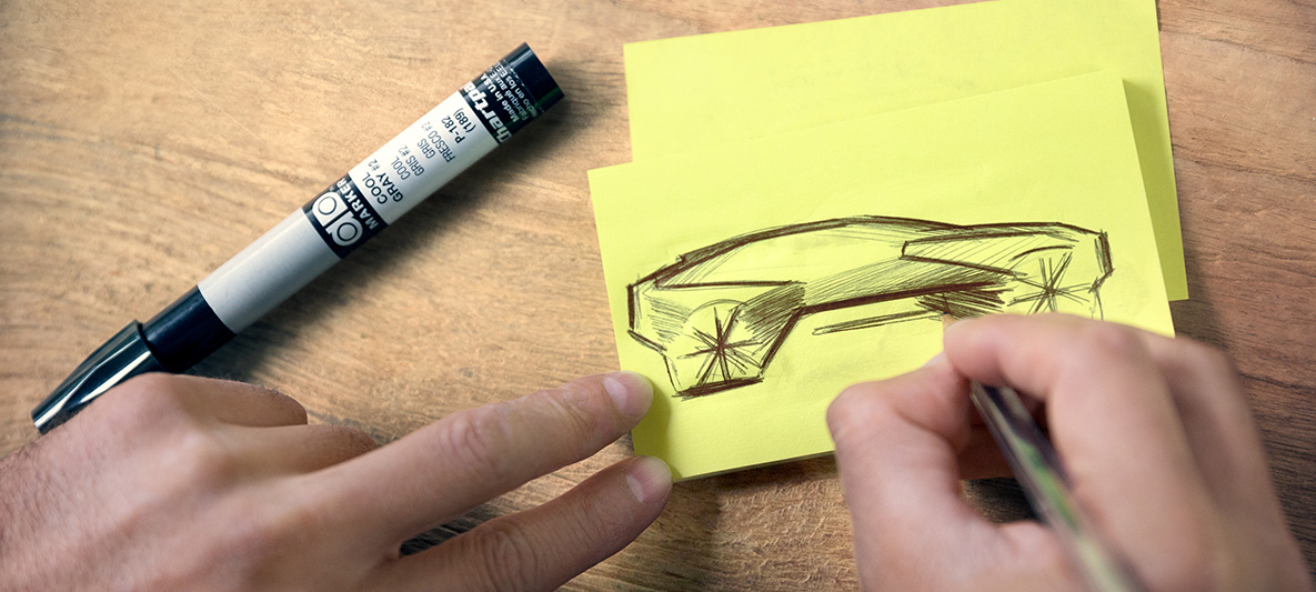 BMW Vision iNEXT -auton luonnos Kädet piirtämässä BMW Vision iNEXT -auton luonnosta post-it-muistilapulle