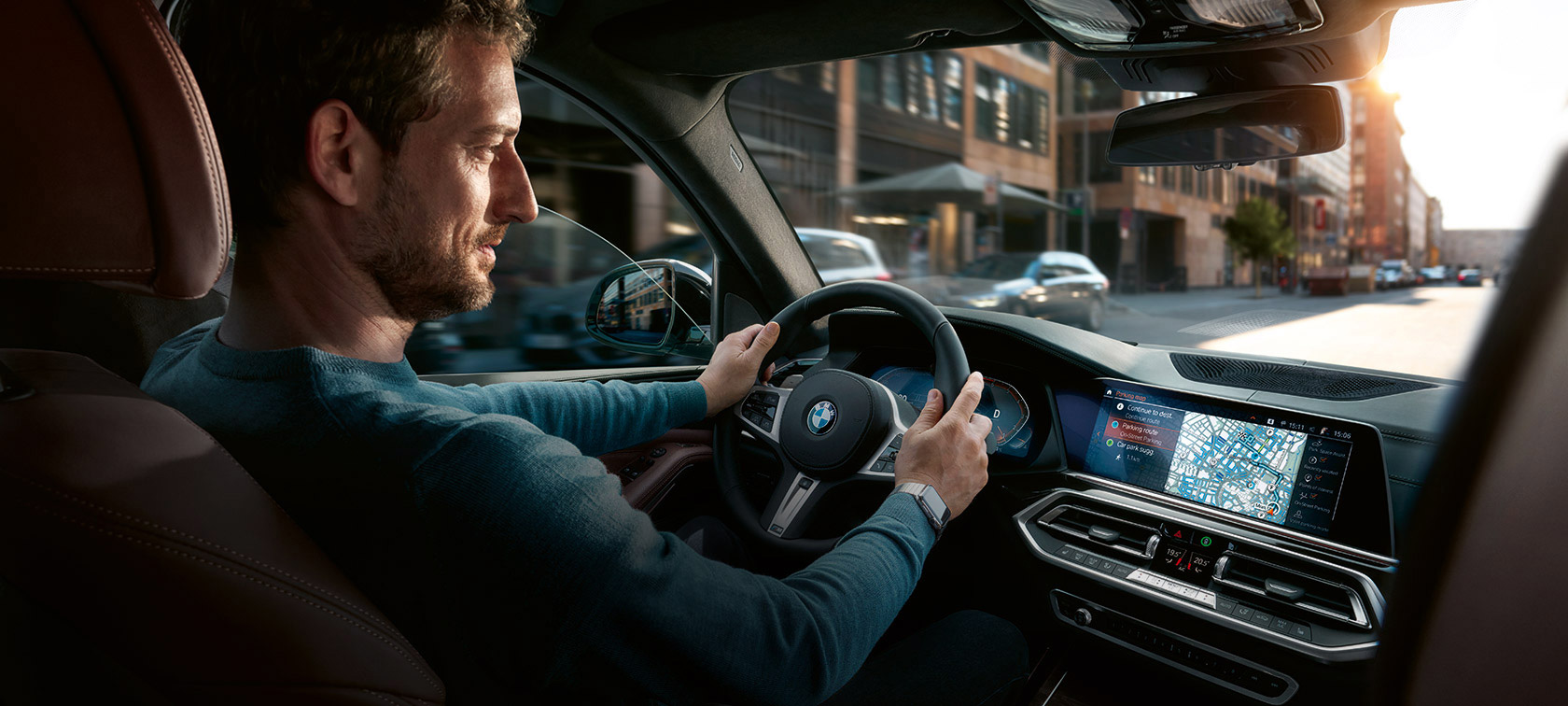 BMW Maps -navigointi Mies ajaa BMW-autolla, jonka monitoiminäytöllä näkyy BMW Maps -navigointi