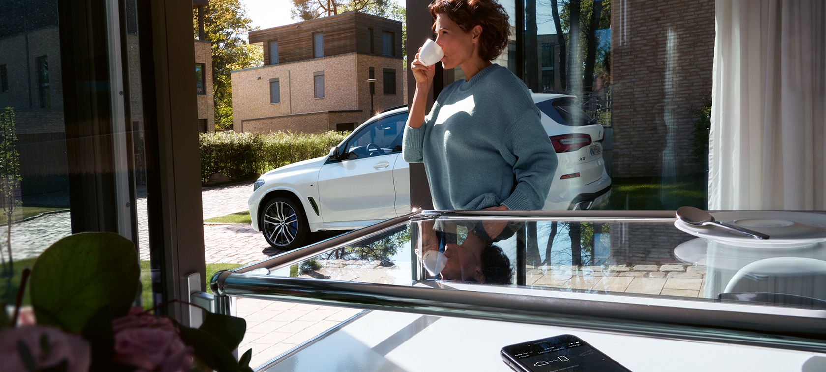 BMW Remote Software Upgrade Nainen juo kupista, kun BMW Remote Software Upgrade päivittää hänen BMW X5 -autonsa ohjelmistoa