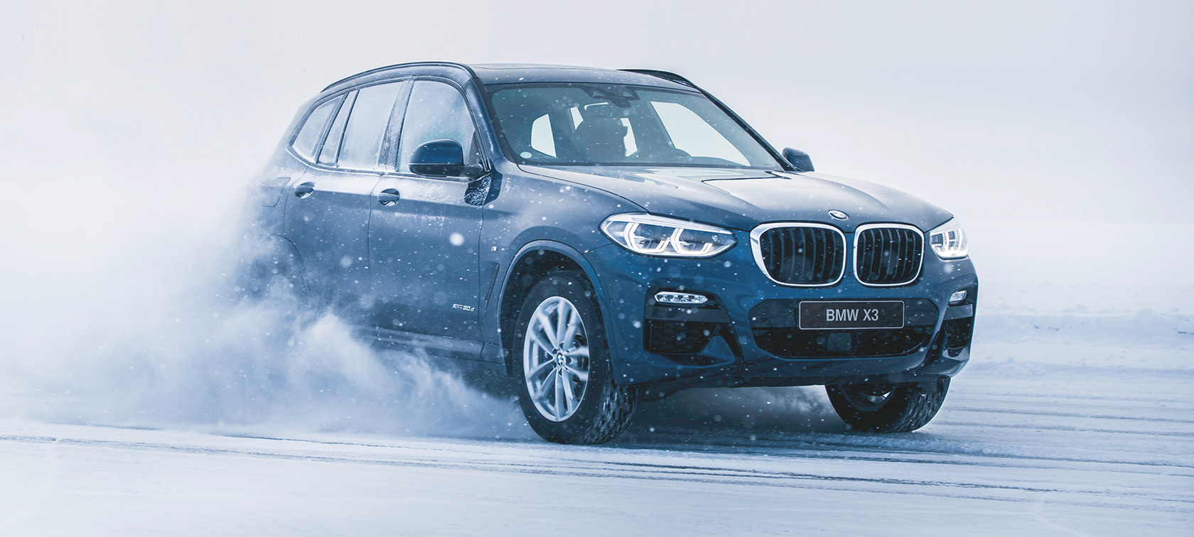 BMW:n syksy- ja talvilisävarusteet BMW X3 lumessa, etuosasta näkyy kolme neljäsosaa