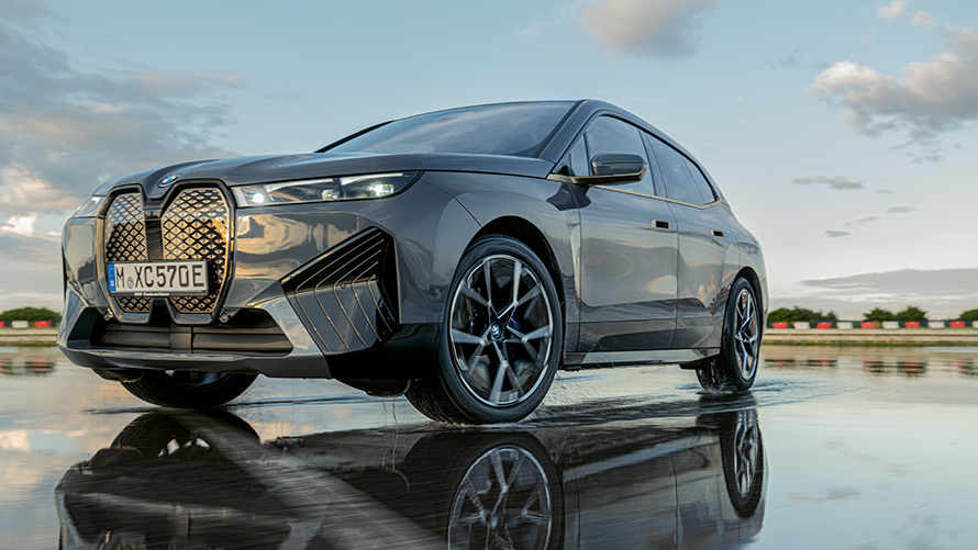 BMW vanteet, kolmen neljäsosan näkymä BMW iX:n (i20) edestä märällä kadulla BMW vanteet, kolmen neljäsosan näkymä BMW iX:n (i20) edestä märällä kadulla