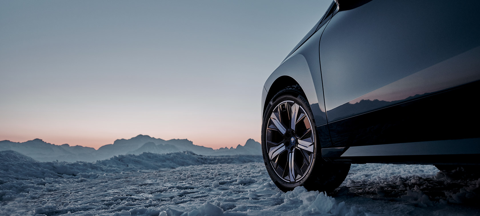 Alkuperäiset BMW vanteet BMW iX (I20) im Schnee vor Bergen Alkuperäiset BMW vanteet BMW iX (I20) im Schnee vor Bergen