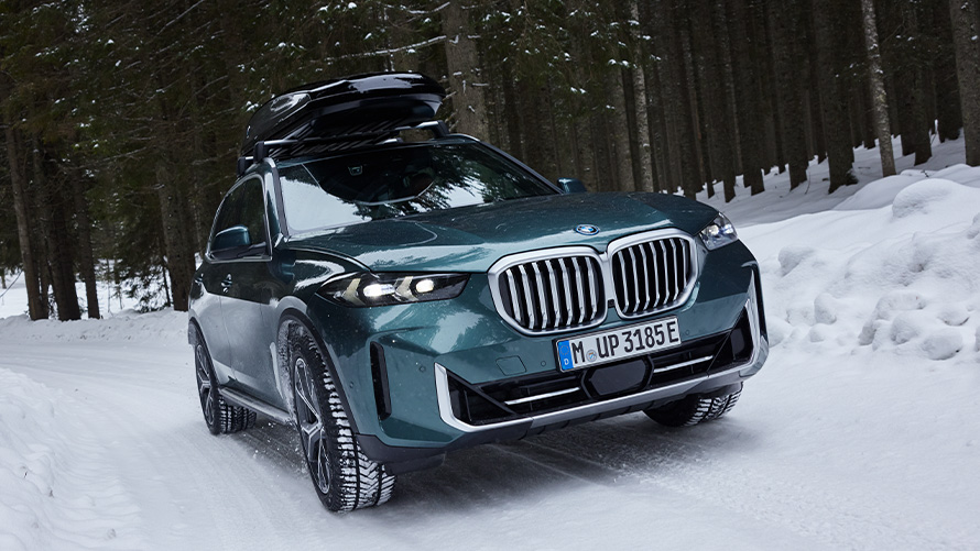 BMW talvirengaspaketti BMW X5:ssä (G05 LCI) lumisella metsätiellä BMW talvirengaspaketti BMW X5:ssä (G05 LCI) lumisella metsätiellä