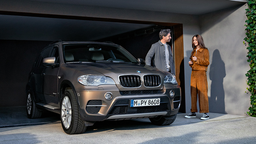 BMW seisoo autotallin edessä mallien kanssa BMW Service 5+ BMW seisoo autotallin edessä mallien kanssa