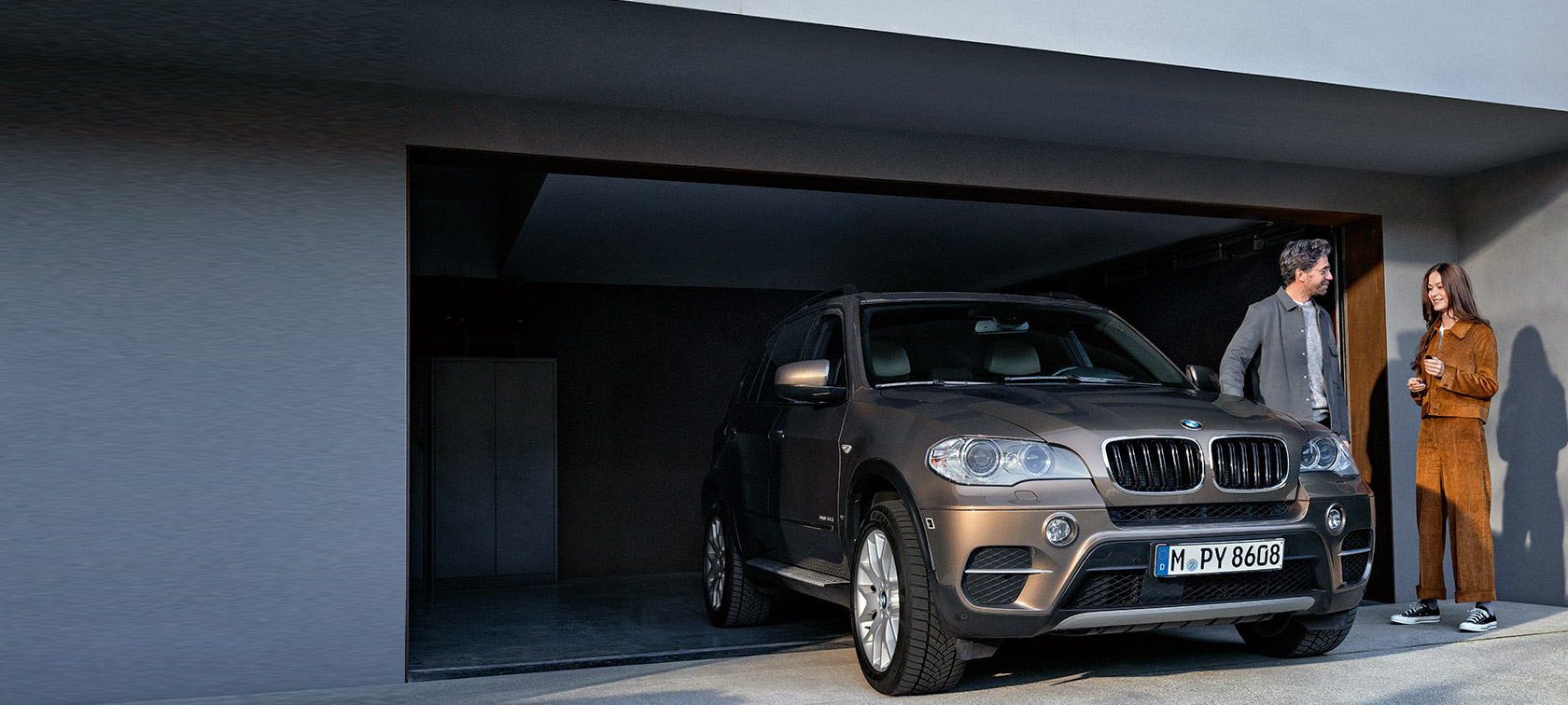 BMW Service 5+ BMW Service 5+ Mies ja nainen autotallin edessä BMW X5:n vieressä