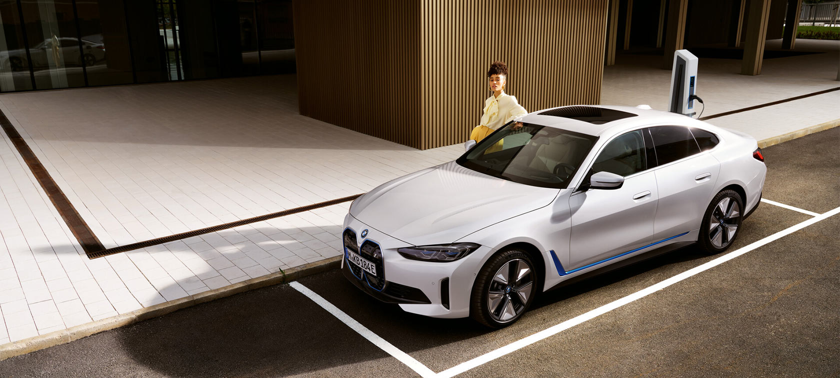 BMW i4 eDrive40 G26 2021 Mineral White 3/4-näkymä järven edessä seisovasta autosta taustalla kukkula